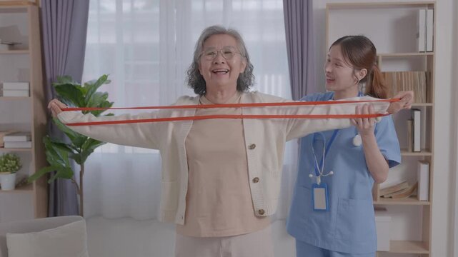 Asian young nurse helping senior elderly woman physical therapy Stretch with elastic in a nursing home. Physiotherapist, Doctor assist Disabled Patients. older rehabilitation health care. paralysis