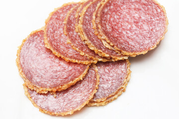 Slices of salami sausage on white background. Round pieces of smoked meat. Traditional cured pork delicacy. Rustic gourmet food for snack. Tasty protein meal for kitchen. Authentic dried meat closeup.
