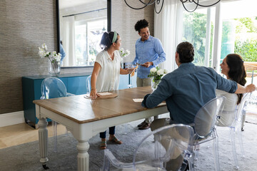 Friends enjoying lively conversation around dining table in bright, modern home