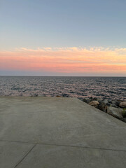 A beautiful sunset over the sea coast, the sun's rays make the concrete pier warmer