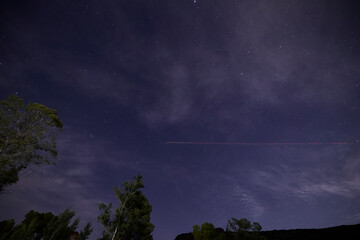 Night sky with stars and airplane light trail