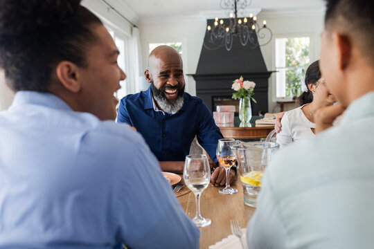 Laughing and conversing, friends at dining table during wedding celebration