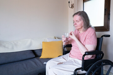 Senior woman in wheelchair taking medication at home