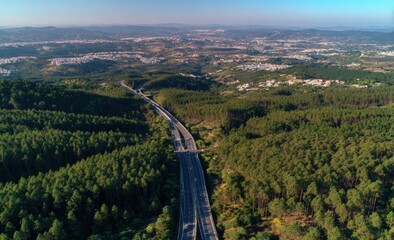 High-angle view of a highway cutting through a forested landscape, overlooking a city