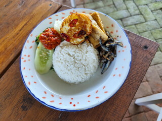 Tempong rice, Tempong rice is equipped with fresh vegetables, salted fish, eggs, chili sauce, tempeh, tofu and other accompaniments. Tempong rice is a typical food from Banyuwangi, Indonesia.