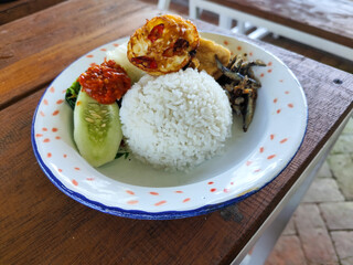 Tempong rice, Tempong rice is equipped with fresh vegetables, salted fish, eggs, chili sauce, tempeh, tofu and other accompaniments. Tempong rice is a typical food from Banyuwangi, Indonesia.