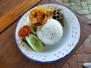Tempong rice, Tempong rice is equipped with fresh vegetables, salted fish, eggs, chili sauce, tempeh, tofu and other accompaniments. Tempong rice is a typical food from Banyuwangi, Indonesia.