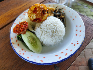 Tempong rice, Tempong rice is equipped with fresh vegetables, salted fish, eggs, chili sauce, tempeh, tofu and other accompaniments. Tempong rice is a typical food from Banyuwangi, Indonesia.