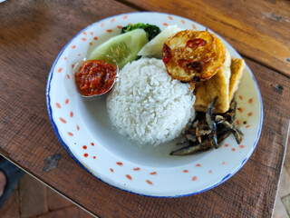 Tempong rice, Tempong rice is equipped with fresh vegetables, salted fish, eggs, chili sauce, tempeh, tofu and other accompaniments. Tempong rice is a typical food from Banyuwangi, Indonesia.