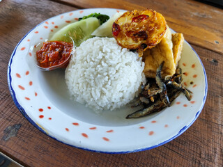 Tempong rice, Tempong rice is equipped with fresh vegetables, salted fish, eggs, chili sauce, tempeh, tofu and other accompaniments. Tempong rice is a typical food from Banyuwangi, Indonesia.