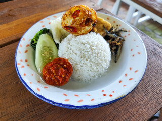 Tempong rice, Tempong rice is equipped with fresh vegetables, salted fish, eggs, chili sauce, tempeh, tofu and other accompaniments. Tempong rice is a typical food from Banyuwangi, Indonesia.