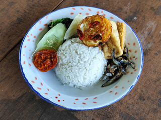 Tempong rice, Tempong rice is equipped with fresh vegetables, salted fish, eggs, chili sauce, tempeh, tofu and other accompaniments. Tempong rice is a typical food from Banyuwangi, Indonesia.