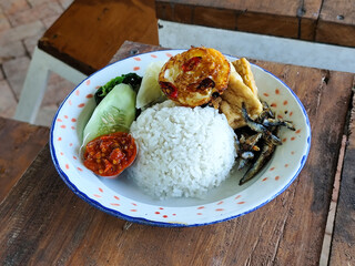 Tempong rice, Tempong rice is equipped with fresh vegetables, salted fish, eggs, chili sauce, tempeh, tofu and other accompaniments. Tempong rice is a typical food from Banyuwangi, Indonesia.