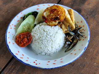 Tempong rice, Tempong rice is equipped with fresh vegetables, salted fish, eggs, chili sauce, tempeh, tofu and other accompaniments. Tempong rice is a typical food from Banyuwangi, Indonesia.
