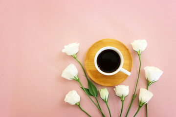 Top view image of coffee cup and flowers on pink pastel background