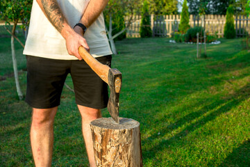 Man holding heavy ax. Axe in lumberjack hands chopping or cutting wood trunks .