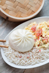 Chinese steamed baozi with rice and tomato egg-stir fry, vertical shot, middle close-up, selective focus