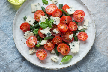 Cherry tomato, green beans and blue cheese salad served on a grey plate, horizontal shot, middle closeup, selective focus