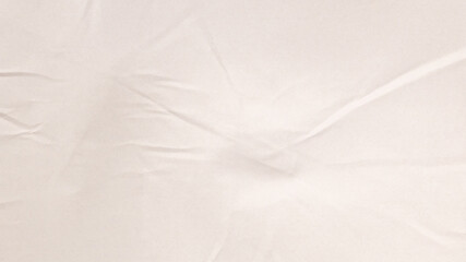 A white fabric lies on a flat surface, revealing a smooth texture adorned with subtle creases. Soft natural light enhances its elegant appearance, creating a serene atmosphere