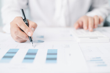 Businessman reviews financial reports, points on chart with pen while analyzing data at office desk working with calculator for accuracy. Concept of accounting, business planning, investment strategy.