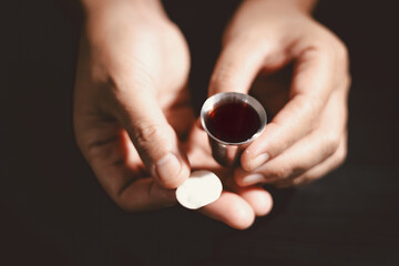 Hands holding communion bread with a wooden bowl and wine cup, symbolizing Holy Communion, the...