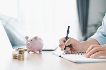Concept of saving money and financial security. Pink piggy bank surrounded by coins on office desk...