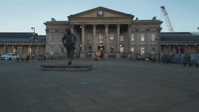 view of Huddersfield Railway Station with the statue of former Prime Minister Harold Wilson at dawn