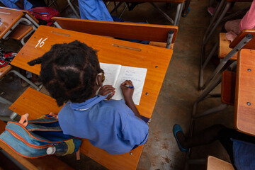 African Schoolgirl Writing in Exercise Book at Classroom Desk