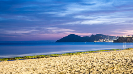 Benidorm, Spain, Serene coastal landscape at dusk, featuring sandy beach, gentle waves, and distant...