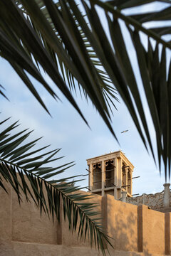 Traditional wind tower in Dubai surrounded by date palm fronds