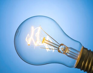 Close-up of glowing incandescent light bulb against a vibrant blue background