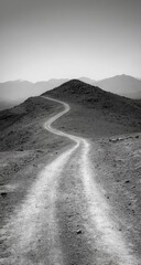 Fototapeta premium A winding dirt road ascends a barren hilltop under a pale sky
