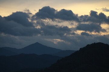 明け方に山にかかる雨雲と朝焼け
