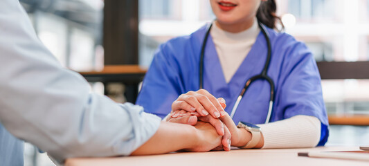 Nurse caring for patient holding hand with compassion in clinic consultation, supportive medical...