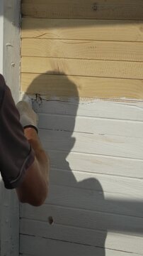 Repairing Wood Wall Hand applying filler to cracks and gaps on exterior wooden planks