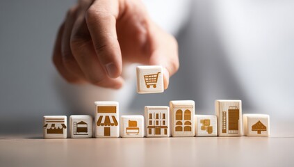 Hand placing a small block with a shopping cart icon on top of a row of small blocks with business icons
