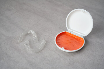 Orthodontic aligner and orange case placed on the table.　Dental orthodontic mouthpiece.