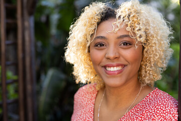 Smiling African American woman enjoying sunny day outdoors in casual attire