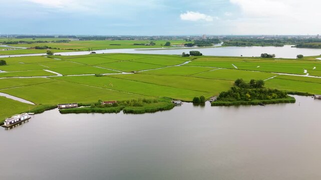 Aerial view of a peaceful rural landscape with a large lake, green fields, and narrow canals. Scattered houses near the water add charm to this well-organized, serene countryside scene.
