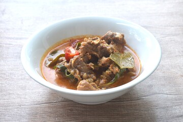 spicy boiled slice beef with lemon leaf in coconut milk red curry soup on bowl