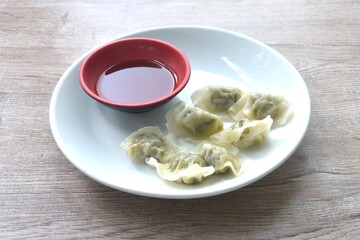 steamed little Chinese dumpling filling mashed pork and shrimp or dim sum on plate dipping spicy soy sauce 