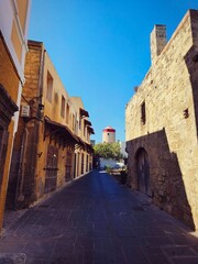 Narrow cobblestone street in the old town of Rhodes, Greece, lined with historic stone buildings and medieval arches.  Mediterranean atmosphere