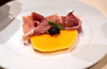 Slices of prosciutto on white plate