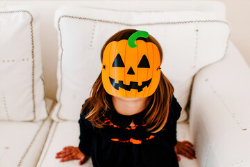 Child wearing orange pumpkin mask and black costume person halloween
