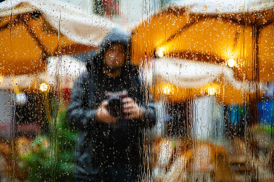 Person with a camera behind a rainy window - Powered by Adobe