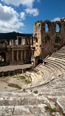 Ancient theater ruins under a partly cloudy sky