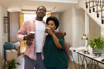 Couple enjoying coffee together in new home, smiling and embracing warmly