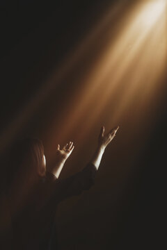 Christian background of people worshipping and praying, praising God with their arms raised toward the bright light.
