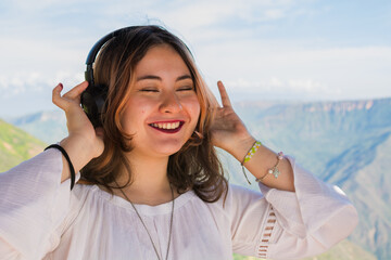 Smiling Latina teenager enjoying music with headphones outdoors in Colombia mountains
