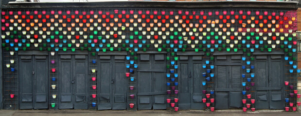Colorful Flower Pots on Dark Wall – Urban Art Installation Background